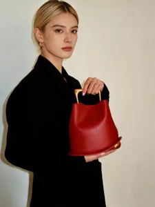 Red leather bucket bag detail featuring a unique architectural gold handle and sphere base.