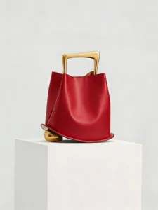 Red leather bucket bag with unique gold handle and sphere accent, stylish niche fashion accessory.