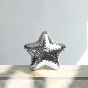 Close-up detail of silver metallic hammered star evening bag showcasing glossy shine texture.