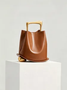 Chic autumn winter brown leather bucket bag featuring unique gold metal handle detail.