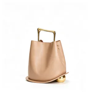 Detail view of the elegant leather bucket bag featuring a unique gold handle and sphere accent.