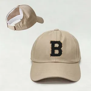 Detalle de gorra de béisbol beige para coleta con parche de letra B negra bordada.