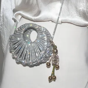 Gros plan détaillé d'un sac de soirée rond ajouré en strass avec lanière en chaîne.