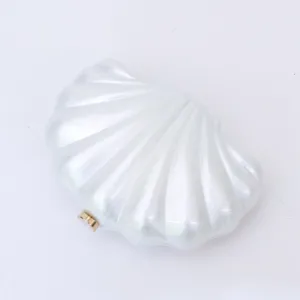 Close-up of pearlescent acrylic shell clutch detail, elegant gold metal clasp texture.