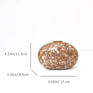 Acrylic clutch bag detail view, marble texture oval evening bag with metal clasp closure.