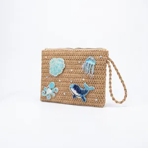 Handcrafted straw clutch featuring intricate beaded marine life embroidery, detail view.