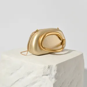 Close-up detail of the gold metallic evening clutch showcasing its unique sculptural handle.
