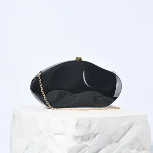 Nahaufnahme Detail der eleganten schwarzen Acryl Abendtasche mit edler goldener Kette.