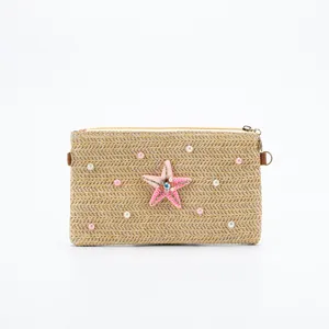 Detailed view of the stylish straw woven shoulder bag featuring a beaded starfish and pearl decor.