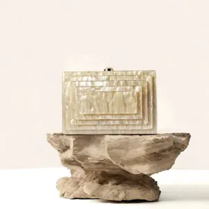 Detailed shot of elegant acrylic box clutch with layered geometric texture and metal clasp.