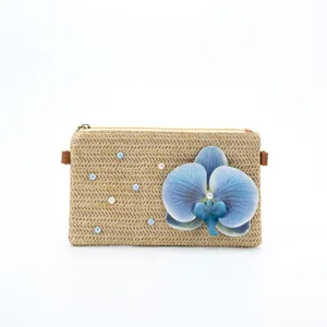 Blue orchid flower detail on straw woven bag with delicate pearl beads accentuation.