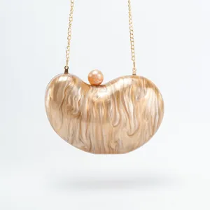 Acrylic bean shaped evening clutch bag detail view with golden chain and pearl clasp for party.