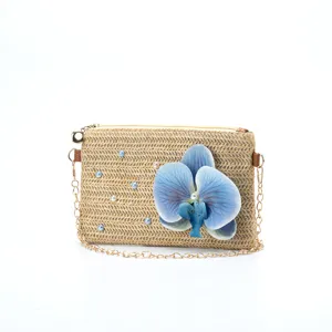Straw woven shoulder bag detail featuring elegant blue orchid and pearls with gold chain.