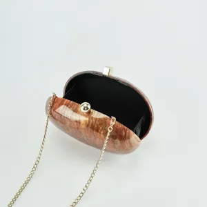Details of the elegant oval acrylic evening clutch bag with glossy marble finish and chain.