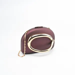 Élégante pochette de soirée rigide bordeaux dotée d'une poignée métal or et d'une chaîne fine.