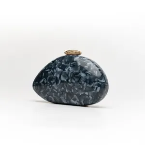 Detailed view of grey marble acrylic evening clutch bag with textured gold clasp hardware.