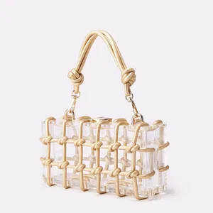 Clear acrylic box handbag featuring a luxury gold woven knotted frame and elegant handle.