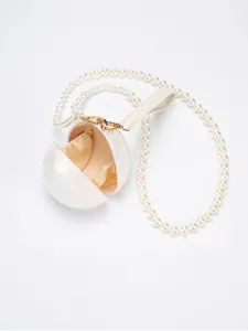 Gros plan détaillé du sac bandoulière en acrylique sphérique blanc avec sangle perle et métal doré.