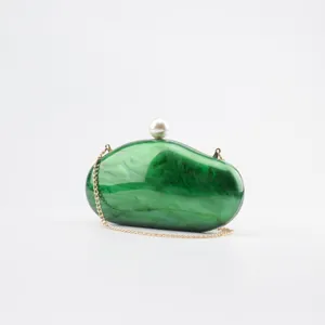 Green marble acrylic clutch bag detail showing pearl clasp and fine gold chain strap.
