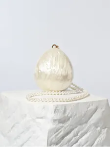 Gros plan détail du sac clutch œuf en acrylique nacré luxueux avec élégante chaîne de perles.