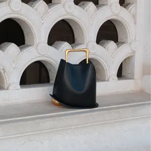 Chic black leather bucket bag featuring unique gold handle and sphere base for women fashion style.