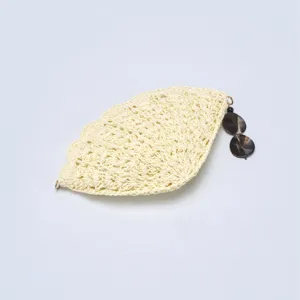 Close-up detail of the beige straw woven shell bag with elegant tortoiseshell pendant.