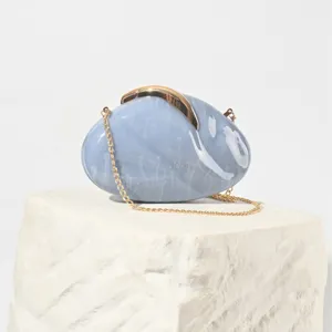 Detailed close-up of blue marble acrylic evening bag with gold leaf lock and chain strap.