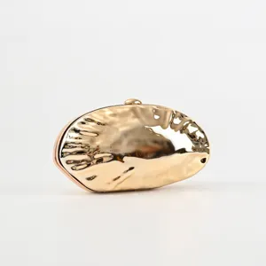 Golden metallic wavy clutch bag for women, elegant evening party shell shaped purse detail.