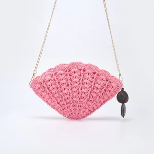 Pink shell-shaped straw woven crossbody bag with delicate chain strap and chic dark charm.