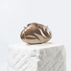 Acrylic evening clutch bag detail showcasing glossy metallic finish and delicate leaf lock clasp.