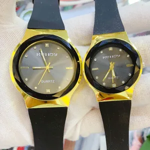 Close-up detail of luxury couple quartz watches with black silicone straps and gold cases.