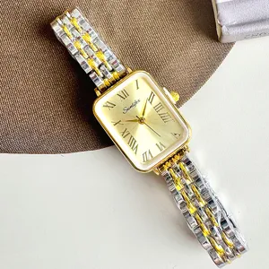 Primo piano di un orologio da donna rettangolare con quadrante dorato e cinturino in acciaio.