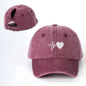 Detail view of the distressed ponytail baseball cap featuring a white heart ECG graphic.