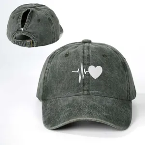 Detail view of distressed gray ponytail baseball cap featuring white heart beat print.