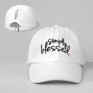 White ponytail baseball cap with embroidered simply blessed text and adjustable strap.