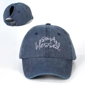 Distressed washed denim ponytail baseball cap with white and pink embroidered blessed text.