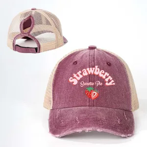 Detail shot of the distressed ponytail mesh baseball cap with strawberry graphic and text.