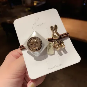 Close-up of cute bunny and coin design hair tie with white backing card detail view.