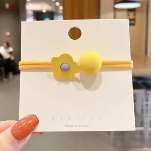 Primo piano dettagliato del grazioso elastico per capelli con fiore giallo e perla sulla carta.