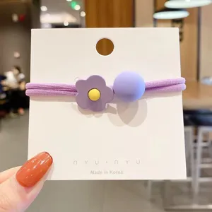 Vista dettagliata di un elastico capelli con fiore viola e perla su carta bianca, stile coreano.