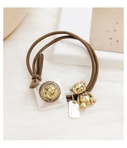 Cute vintage brown hair tie featuring a golden bear charm and classical coin pendant detail.