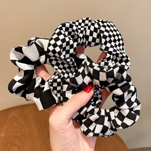 Schicker schwarz-weißer Haargummi mit Karomuster, weicher Stoff für stilvolle tägliche Frisuren.