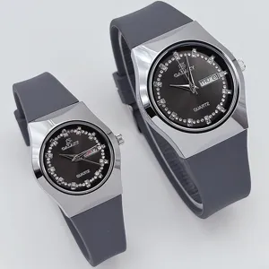 Vista detallada de relojes de pareja con correas de silicona gris y esferas de diamantes.