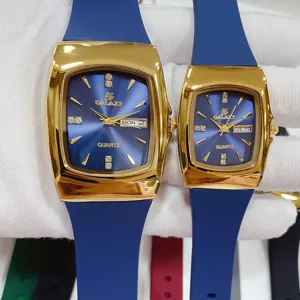 Paar quartz horloge met blauwe siliconen band en gouden tonneau wijzerplaat met datum.