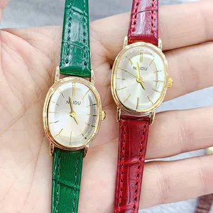 Detailed view of oval quartz wristwatches with green and red leather straps and white dials.