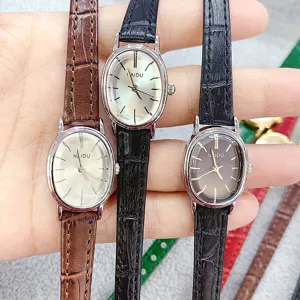 Detailed view of oval quartz watch with slim leather strap, elegant dial and metal case.