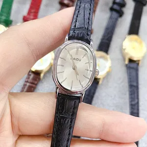 Detail view of minimalist oval quartz watch with black leather strap and clean silver dial.