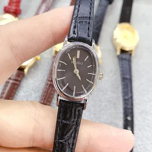 Close-up detail of women's oval quartz watch with black leather strap and simple dial.