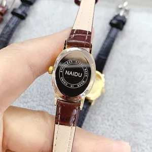 Close-up detail of the vintage oval quartz watch with brown leather strap and steel back.
