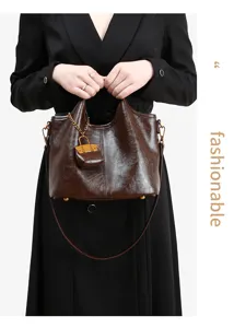 Detail view of the elegant brown leather bucket bag featuring a chic metal chain pendant.